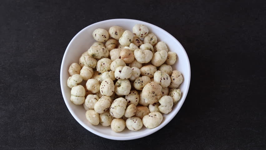 Bowl with puffed Lotus seed. Indian Organic Makhane Makhana puffed lotus seed or Fox nuts. Flavoured Prickly Water Lily. Edible seeds popular in India