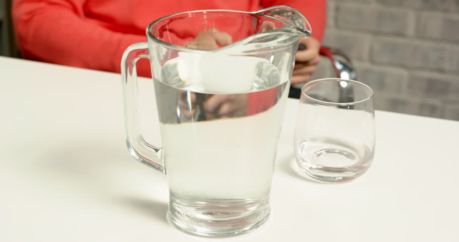 Lifestyle videos indoor of people doing activities at office people in an office pour and drink water from a glass pitcher. these individuals engage in daily tasks while staying hydrated.