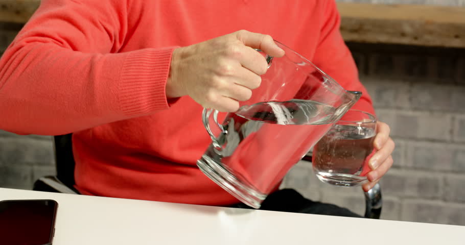 Lifestyle videos indoor of people doing activities at office people in an office pour and drink water from a glass pitcher. these individuals engage in daily tasks while staying hydrated.
