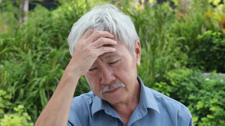 Unwell and mentally sick old Asian senior man having both chronic and acute headache