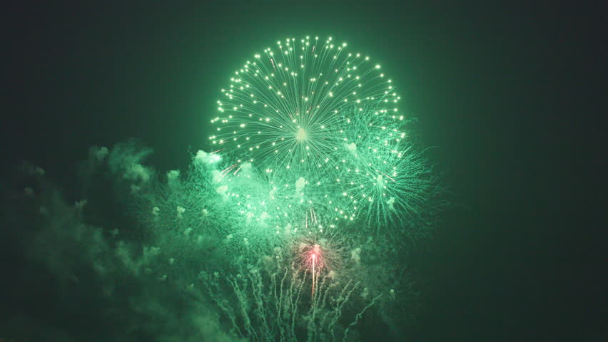Red and Green Fireworks Burst Over Water