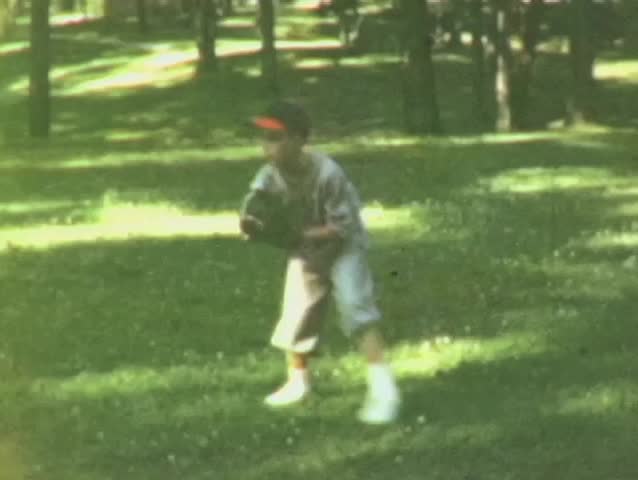 Young baseball player in green grass plays catch in summertime in St. Louis, Mo.