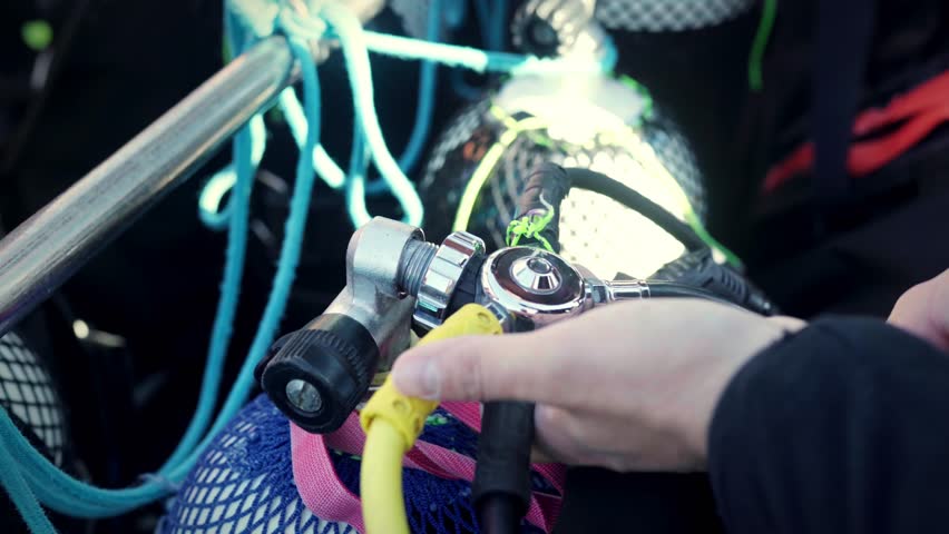 Diver attaching regulator to scuba tank during pre-dive check on boat