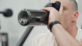 Close up of fitness fanatic drinking water during break with relief on face, seated on gym bench, arm raised gripping bottle firmly, sweat visible under gym lights after intense workout - Powered by Shutterstock - Get 15% off with code: PIKWIZARD15