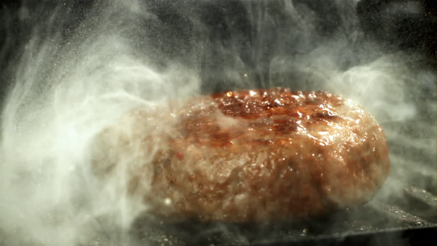A beef burger falls into a hot pan with a splash of oil. Filmed on a high-speed camera at 1000 fps. High quality FullHD footage