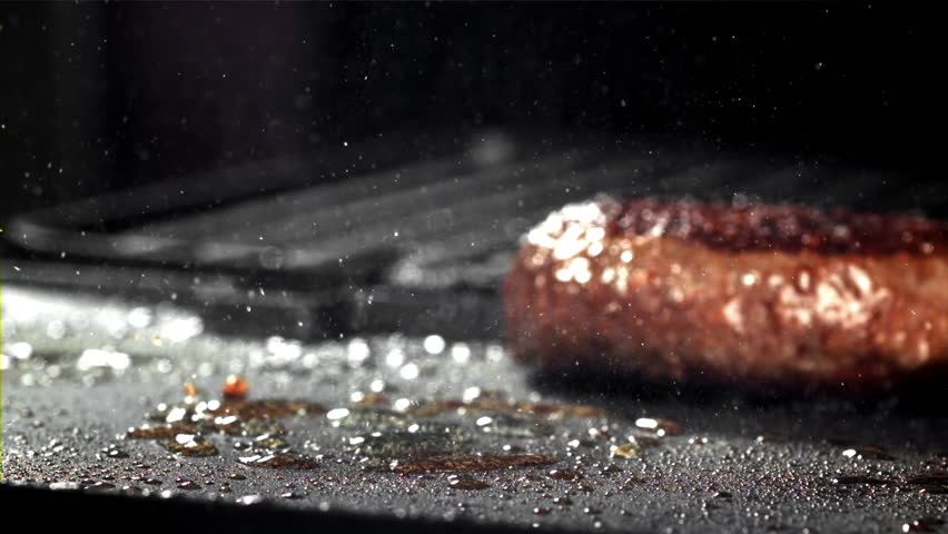 A beef burger falls into a hot pan with a splash of oil. Filmed on a high-speed camera at 1000 fps. High quality FullHD footage