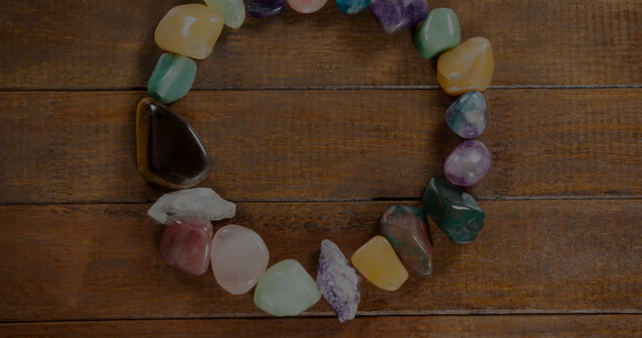 Showcasing open gemstone circle forming on wooden tabletop, highlighting polished colorful stones. Jewelry, spirituality, natural, craft, wellness, meditation, bohemian