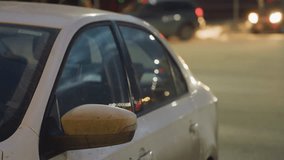Parked white car on roadside during night with blurred reflections of moving cars and pedestrians, glowing street lights and headlights creating soft atmospheric urban scene with motion and contrast - Powered by Shutterstock - Get 15% off with code: PIKWIZARD15
