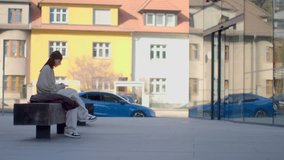 A woman on a city bench engages in life on her phone, highlighting urban living while reading a book, showcasing her multifaceted personality - Powered by Shutterstock - Get 15% off with code: PIKWIZARD15