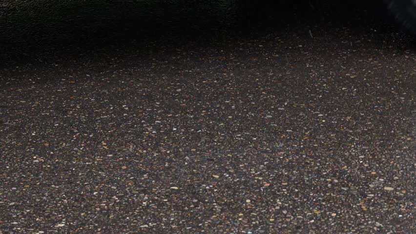 Car wheels spinning on wet asphalt road on a rainy day