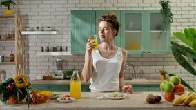 Healthy eating concept. Young woman at the table in the kitchen preparing spring rolls for healthy lunch, pours orange juice in glass, eats fresh spring rolls, and drinks juice. Slow motion. - Powered by Shutterstock - Get 15% off with code: PIKWIZARD15
