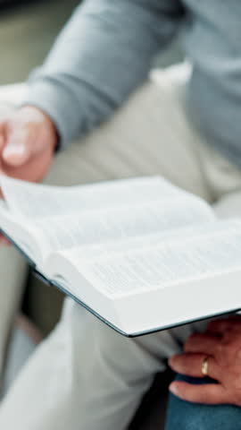 Hands, bible and religion in home, couple and together for studying, point and faith in lounge. Senior people, spiritual jewellery and book for Christian knowledge, scripture and holy gospel at house