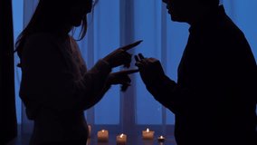 Silhouettes of a man and a woman facing each other in a dimly lit room and arguing, against a background of blue curtains and lit candles. Relationship Concept. - Powered by Shutterstock - Get 15% off with code: PIKWIZARD15