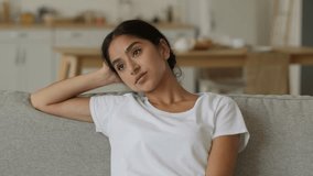 Stressed Arabian woman Indian girl tired frustrated lady fatigued overworked female at home sitting on couch cozy comfortable sofa relaxing resting health problem relaxed pause break air conditioner - Powered by Shutterstock - Get 15% off with code: PIKWIZARD15