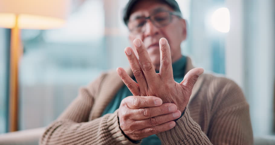 Arthritis, medical and senior man with hand pain, injury or muscle sprain in living room at nursing home. Osteoporosis, parkinson disease and closeup of elderly male person with wrist inflammation.