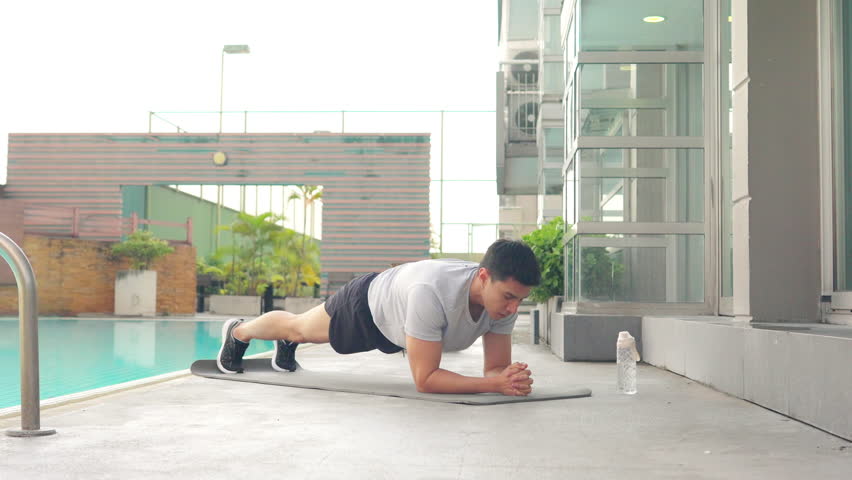 Healthy wellness Asian man sport training fitness plank workout exercise at stadium gym. Young man in sportswear do push-up plank exercise abdominal muscles improve core strength and stability.
