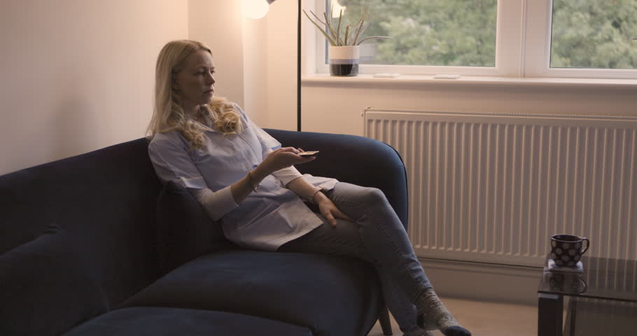 Woman watching tv, news media and movie, cable show and broadcast in home lounge, living room sofa and retirement. Lady relax, television subscription and streaming entertainment