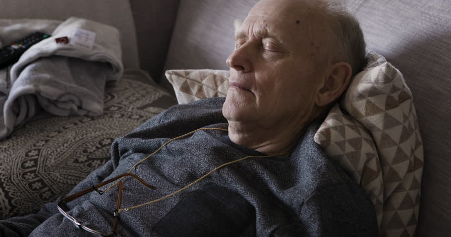 Senior man, tired and sleeping on a couch in the living room at a nursing home for rehabilitation for recovery, energy and health. Sleep, relax and calm elderly male on sofa for peace and rest