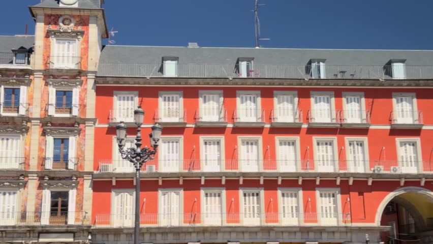 Detailed view of the historic colorful facades of Plaza Mayor in Madrid, Spain, under a clear blue sky, showcasing architecture and cultural heritage