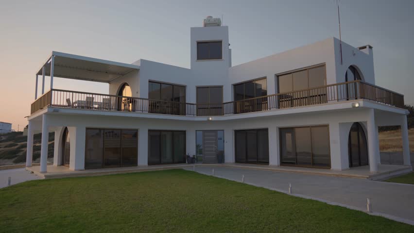 Elegant two-story luxury villa in Cyprus, bathed in golden sunset light. Captured in cinematic tones, perfect Mediterranean real estate for vacation, investment, or dream living.