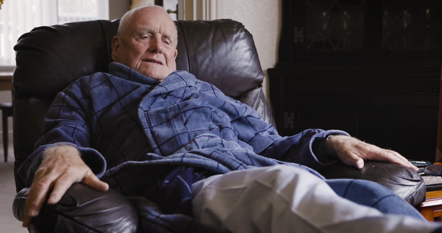 Rehabilitation, rest and senior man on sofa laying to relax, recover and stretch legs after knee surgery. Healthcare, retirement and elderly male resting after physical therapy and healing at home