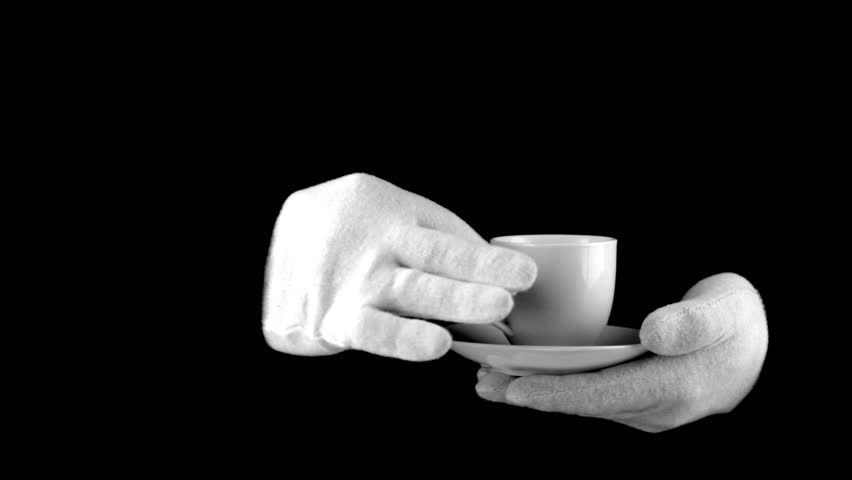 Black background. Man (face - behind the scenes) in white gloves try coffee from