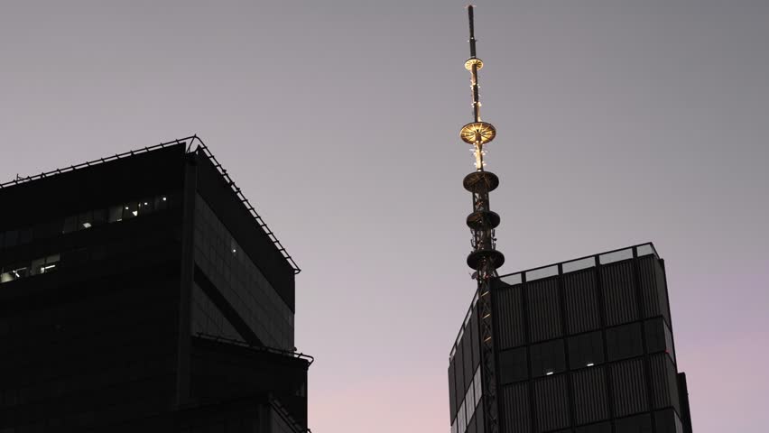 Dark glass skyscrapers at dusk in Warsaw, Poland. Futuristic cityscape with modern towers, steel structures, cinematic night lights and TV Tower.