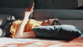 A woman relaxes on a couch, comfortably lying down with a smartphone in hand. Her casual attire and the serene environment create a peaceful atmosphere, ideal for unwinding after a long day. - Powered by Shutterstock - Get 15% off with code: PIKWIZARD15