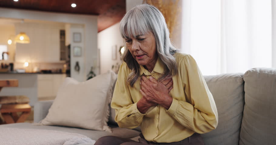 Senior woman, chest pain and sofa with heart attack for cardiac arrest, illness or panic at home. Elderly, female person or patient with sore breathing for bronchitis, lung disease or inflammation