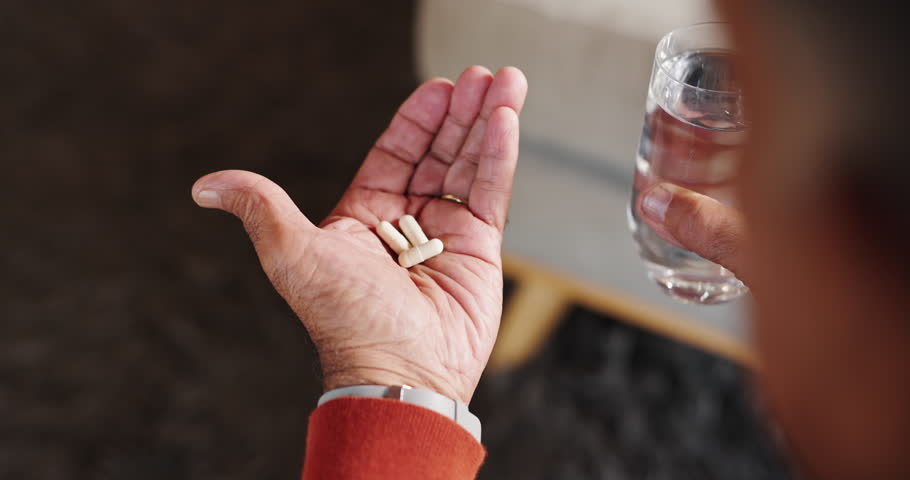 Senior, hands and pills with water in home for prescription medication, healthcare treatment and parkinsons disease. Above, old person and tablets for wellness supplements, healing or medical illness