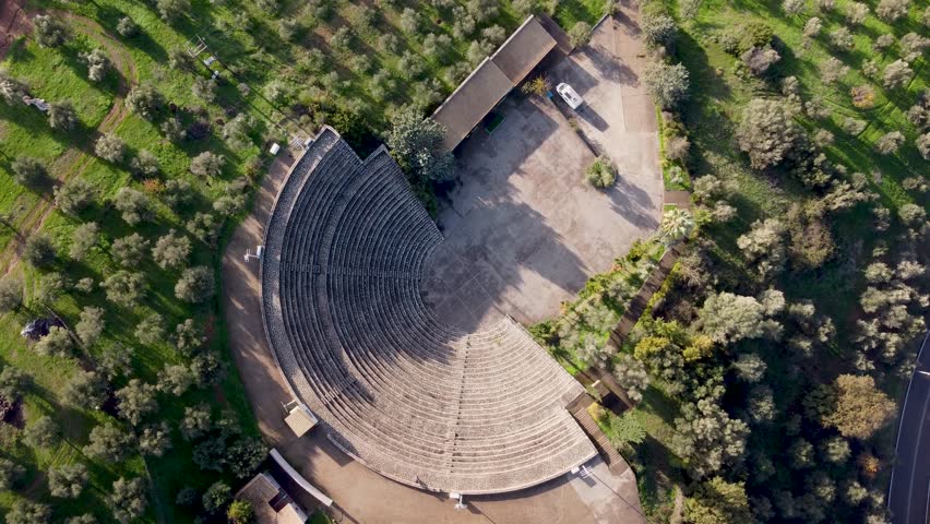 4k top-down drone shot of the historic Epidaurus amphitheater in Olympia, Peloponnese, Greece, surrounded by lush greenery and bathed in gentle sunlight, ideal for documentary use.