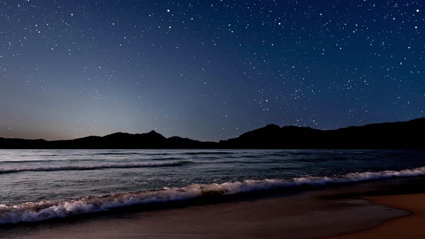 Sunrise over the sea with gentle waves and fading stars against the background of mountains