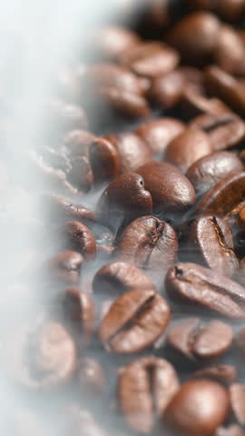 Vertical closeup roasted coffee beans or seeds background with white smoke texture in slow motion