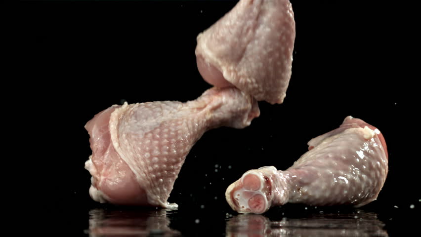 Raw chicken legs falling on black background. Filmed on a high-speed camera at 1000 fps. High quality FullHD footage