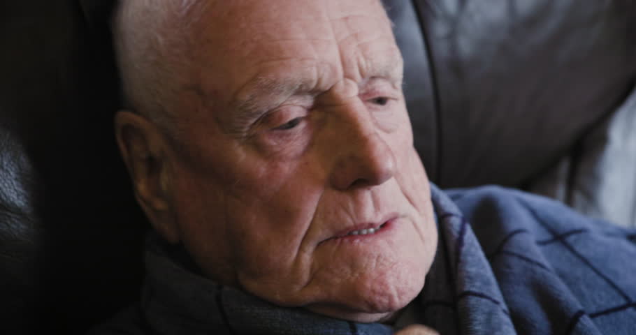 Sleep, nap and senior man on a sofa in a gown while relaxing in the living room at his home. Cold, insomnia and elderly guy in retirement sleeping for rest on a couch in his house in Australia.