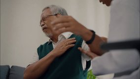 Elderly Asian man holding shoulder in pain during consultation with female doctor at clinic. Medical care and diagnosis for musculoskeletal discomfort. - Powered by Shutterstock - Get 15% off with code: PIKWIZARD15