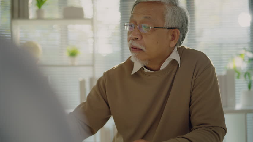 Asian elderly man expressing concern during a medical consultation with a female doctor, illustrating emotional communication and healthcare support in the hospital.
