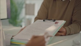 Asian female doctor holding patient medical history clipboard while consulting elderly man in clinic. Close-up of real healthcare documentation. - Powered by Shutterstock - Get 15% off with code: PIKWIZARD15