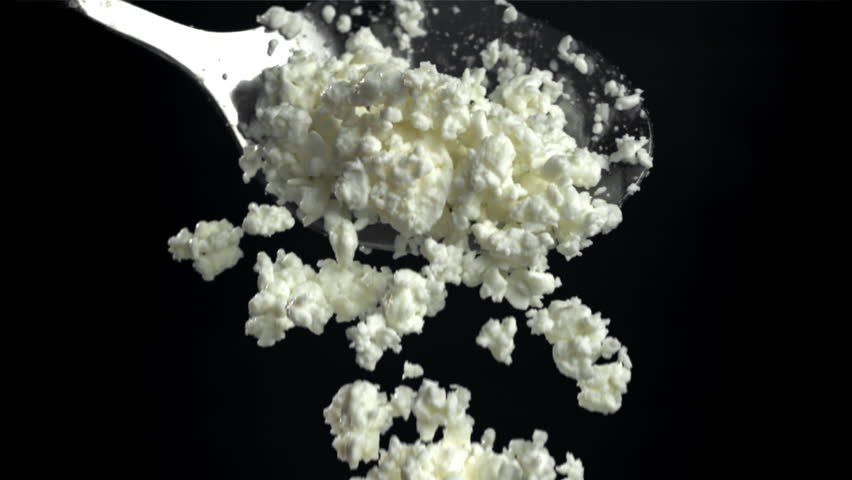 Fresh cottage cheese falling from a spoon on a black background. Filmed on a high-speed camera at 1000 fps. High quality FullHD footage