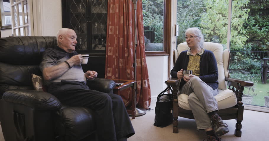 Coffee, talking and love with a senior couple sitting in the living room of their retirement home together. Tea, conversation or bonding with a mature man and woman chatting in the lounge of a house