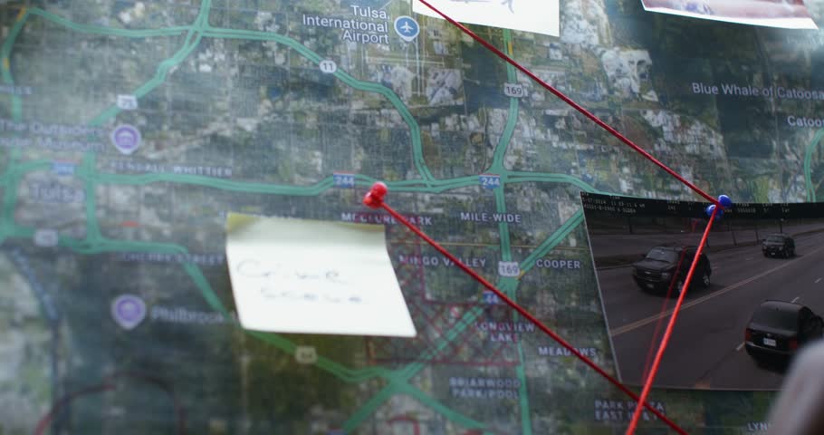 Two detective colleagues are examining the map in the office. Close-up of their hands, unrecognizable persons