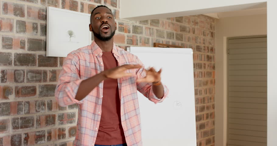 Lifestyle videos indoor of people doing activities at home, presenting data, man standing by whiteboard with graph in casual home setting. giving presentations, half body, with hand gestures