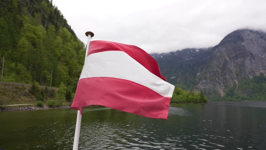  Austrian Flag. The Austrian flag is waving against a backdrop of nature. Travel concept. Boat tour in summer in Austrian Alps. 