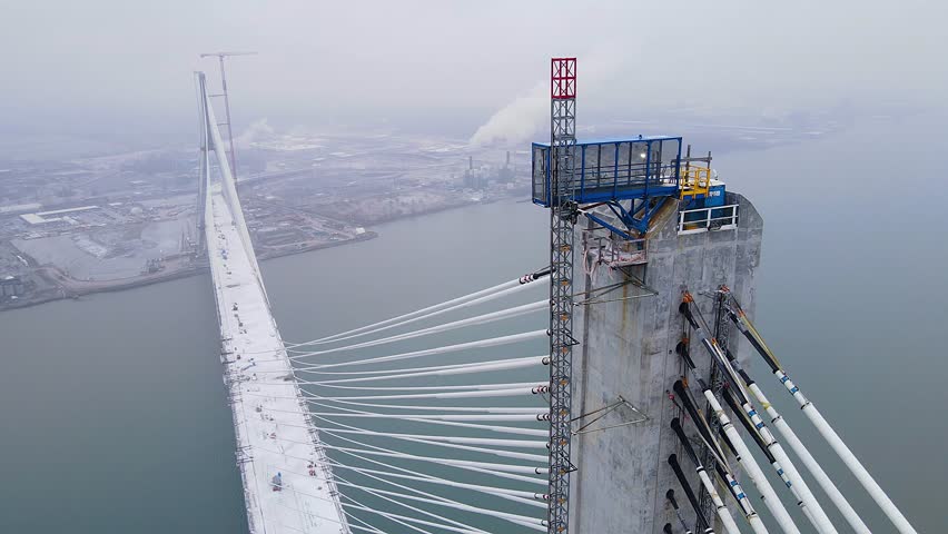 Aerial video of Gordie Howe International Bridge tower with cable anchors. Gordie Howe Bridge still under construction in winter.