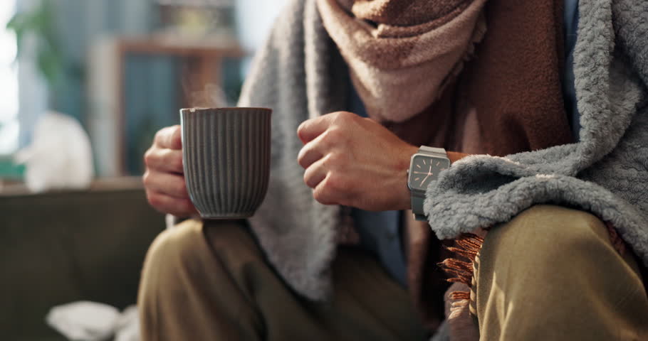 Sick, hands and tissue with tea on sofa for flu recovery, ginger treatment and healing. Closeup, person or blanket with honey drink for influenza virus, health benefits and remedy for illness in home