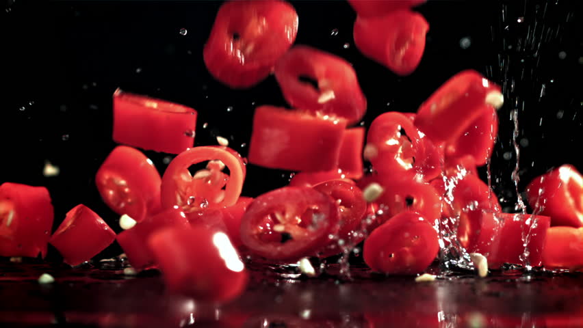 Sliced chunks of chili pepper falling on a black background. Filmed on a high-speed camera at 1000 fps. High quality FullHD footage
