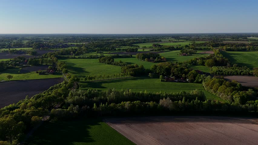 Tranquil and peaceful green landscape of America at sunset time. Spring day with agricultural farm fields and tree avenues. Drone dolly wide shot. Serene atmosphere in american countryside.