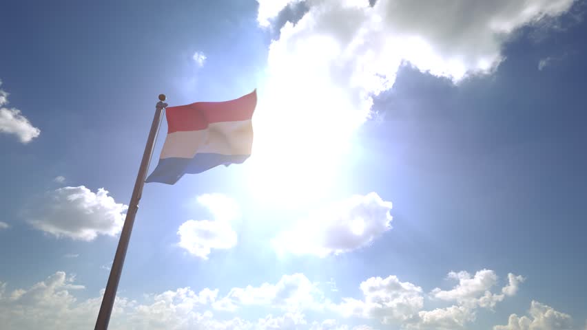 Luxembourg Flag waving on a Flagpole from a Moving Angle in front of a blue sky with clouds