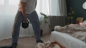 Athletic senior man in comfortable t-shirt and pajama pants practicing kettlebell swings and presses during weightlifting workout in bedroom at home - Powered by Shutterstock - Get 15% off with code: PIKWIZARD15