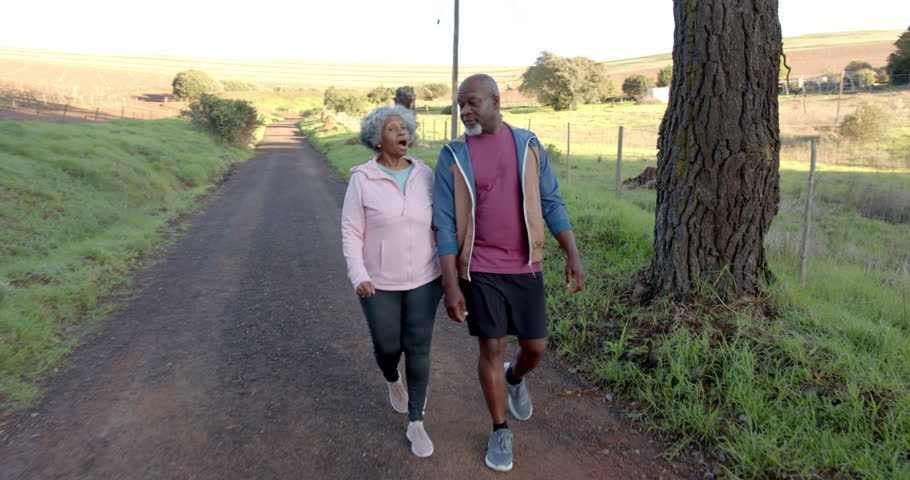 Lifestyle videos outdoor of people doing activities, walking on rural path, senior couple enjoying outdoor exercise together. a couple of people walking and conversing with each other